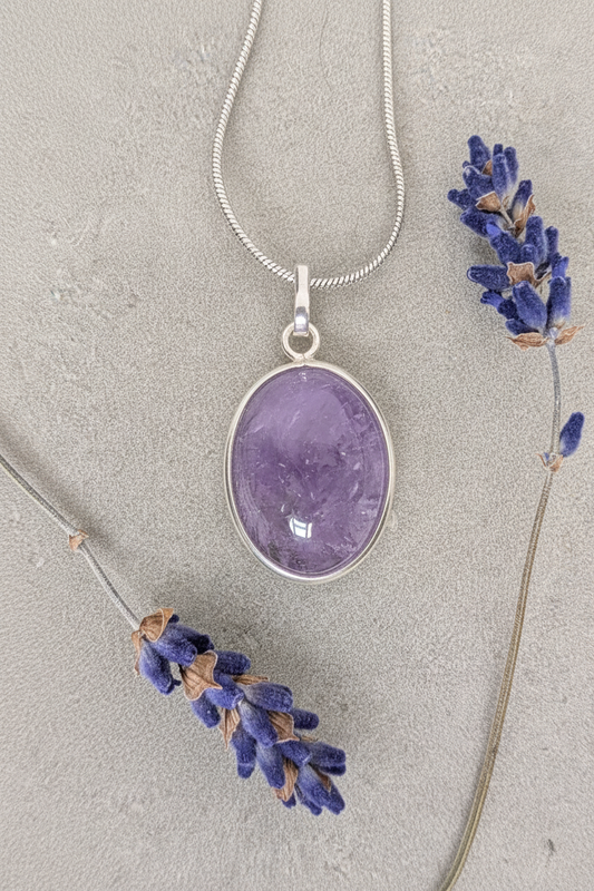 Amethyst oval cabochon pendant in sterling silver bezel on stainless steel snake chain, styled with dried lavender