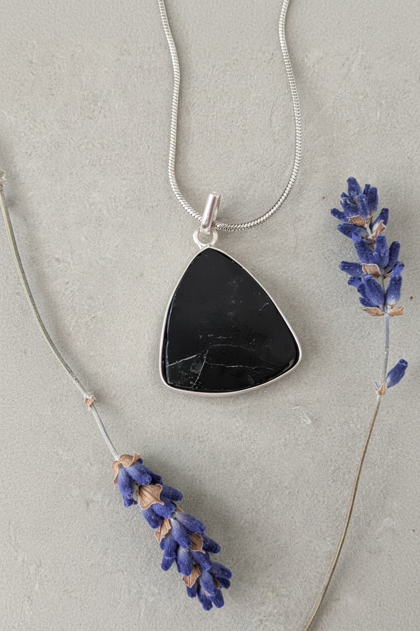 Black tourmaline triangle pendant in sterling silver bezel on stainless steel snake chain, styled with dried lavender