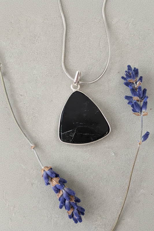 Black tourmaline triangle pendant in sterling silver bezel on stainless steel snake chain, styled with dried lavender